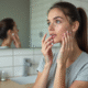 Jeune femme appliquant un serum visage dans sa salle de bain